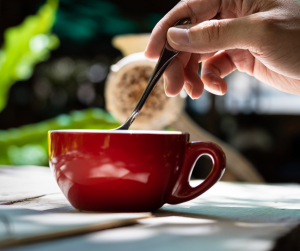 someone stirring red coffee cup with spoon outside